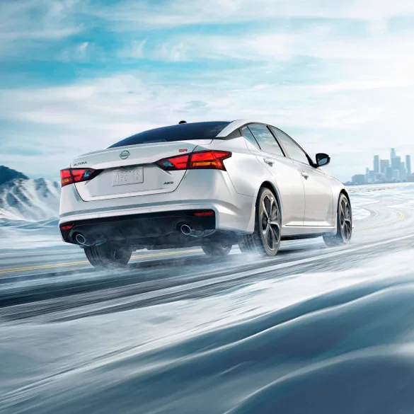 2027 Nissan Altima in white seen from behind driving in snowy landscape illustrating all-wheel drive at Gerweck Nissan in Monroe MI